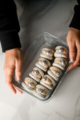 Female hands holding a rectangular glass container with beautiful shell-like macaroons