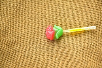 pink rose lollipop candy stabbing in plastic stick on fabric background