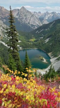 Red-yellow leaves on the background of the mighty mountain peaks. Mountains and lake in North Cascades national park, USA. Autumn in the mountains. Nature of United States of America, vertical shot