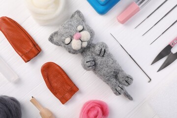 Felted cat, wool and different tools on white wooden table, flat lay