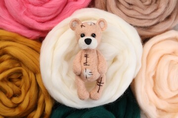 Obraz na płótnie Canvas Felted bear on colorful wool, top view