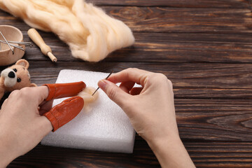 Woman felting from wool at wooden table, closeup. Space for text