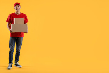 Happy courier with parcels on yellow background. Space for text
