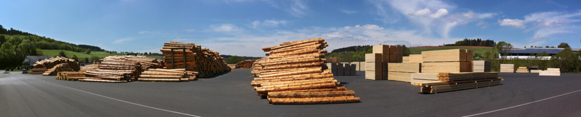Panoramic view of stacked logs and lumber products on a sawmill storage area in Germany