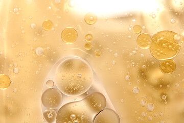 Golden circular oil bubbles floating on a clear water background.