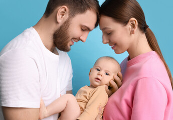 Happy family. Parents with their cute baby on light blue background