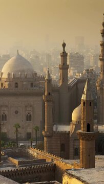 Panning shot of Mosque of Sultan Hassan, Cairo, Egypt at sunset. Cairo city in light fog in the rays of setting sun. High quality vertical shot
