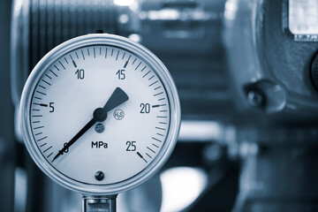 A black and silver pressure gauge is attached to a pipe. The gauge is set at a pressure of 25 Mpa