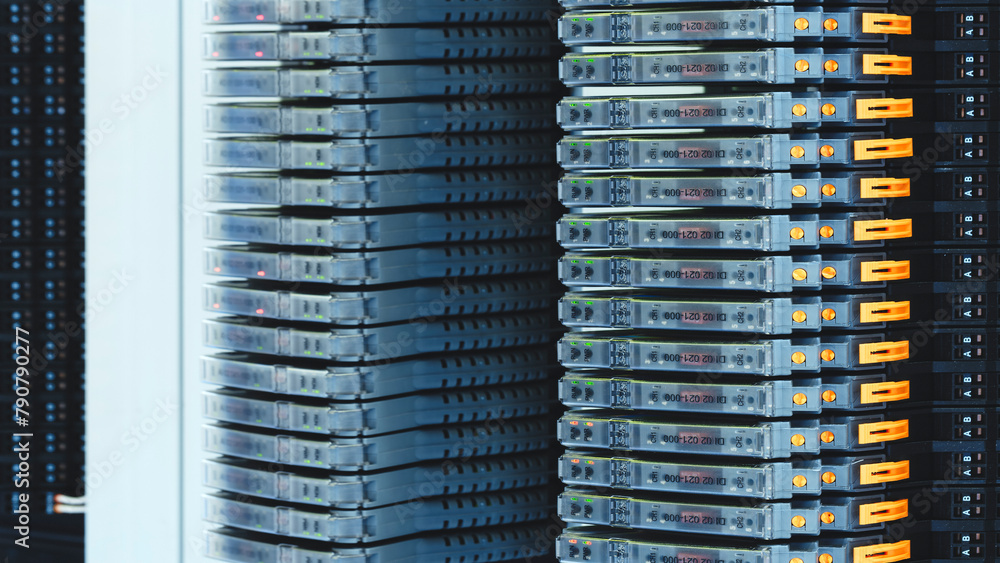 Poster a row of servers with orange connectors on the side. the servers are stacked on top of each other