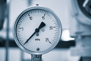 A black and silver pressure gauge is attached to a pipe. The gauge is set at a pressure of 25 Mpa
