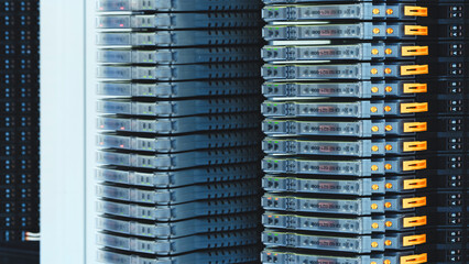 A row of servers with orange connectors on the side. The servers are stacked on top of each other