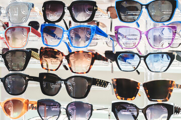 A row of sunglasses on display in a store. The sunglasses are of various colors and styles, including some with a cat print