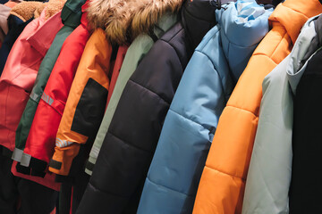 A row of colorful coats hanging on a rack. The colors include red, blue, green, yellow, and black