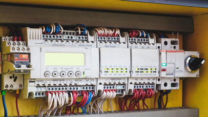 A panel of electrical wires with a green light on it. The wires are connected to a yellow box