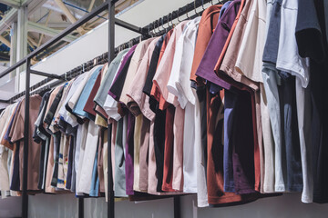 A rack of clothes with a variety of colors and styles. The clothes are hanging on a rack, and the colors include white, pink, purple, and brown