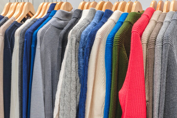 A rack of clothes with a variety of colors including blue, green, and red - Powered by Adobe