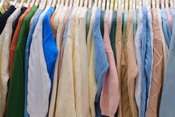 A rack of sweaters with a variety of colors and patterns. Scene is cheerful and colorful