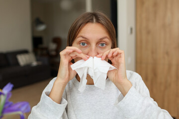 Allergy, flu, cold, rhinitis. Funny face of sick woman with paper tissues inside nose from runny...