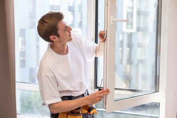 a repairman repairs, adjusts or installs metal-plastic windows in the apartment. glazing of...