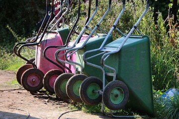 Close-up of green and pink wheelbarrows positioned upright in a row
