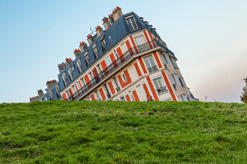 Sinking house on Montmartre hill taken with funny angle, Paris, France at sunset. Optical illusion