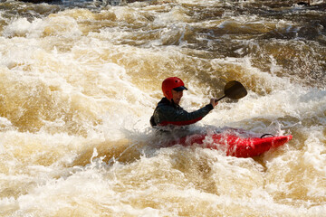 A Man In A Red Kayak Is Paddling Through A River