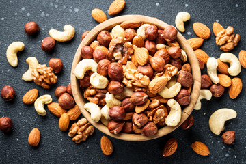 Nuts assortment at black background. Almond, hazelnut, cashew in wooden bowl.