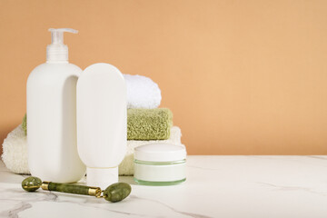 Skin care products in the bathroom. Face cream, serum bottle, jade roller and stack of towels. - 790812484