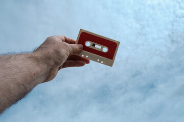 Vintage cassette held by hand against the sky.