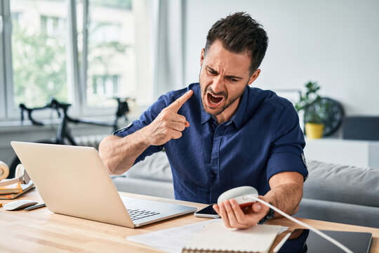Furious angry man screaming at smart speaker while working from home