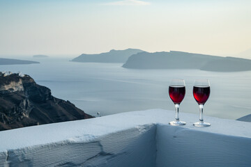 two glasses of red wine on the terrace in greek, beautiful sunset over the ocean or sea, summer vacation or holiday