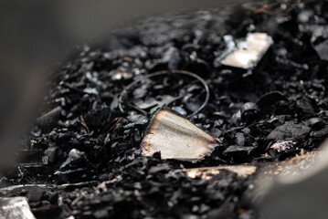  A burnt book on a pile of ashes, the remains of pages in a burnt house.