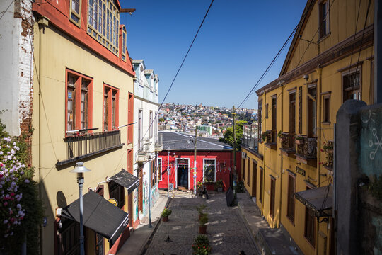 Casas e vielas de Valparaíso, Chile, em dia ensolarado de verão. A arquitetura colorida se destaca sob o céu azul, capturando a essência vibrante da cidade costeira.