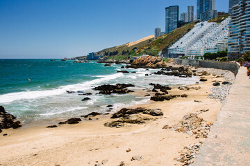 Praia Cochoa em Viña del Mar, com a praia em primeiro plano e os prédios ao fundo em dia ensolarado - obrazy, fototapety, plakaty