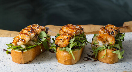 Toasts with fried shrimp and salad mix. Delicious snacks with seafood