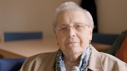 Confident old woman looking at camera sitting in geriatric