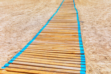 Wooden walkway in the sand of the beach. Sandy coast path 