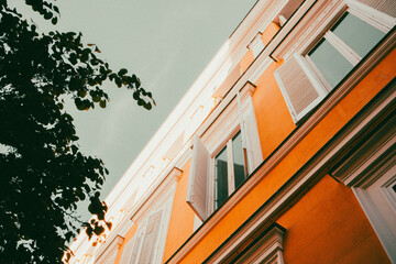An old vintage orange apartment building details with white wooden window shutters bottom view....