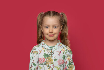 Little cheerful girl in a light dress on a pink background.