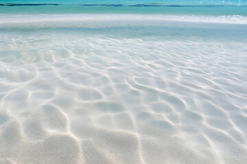Crystal clear waters and white sandy beach under sunlight