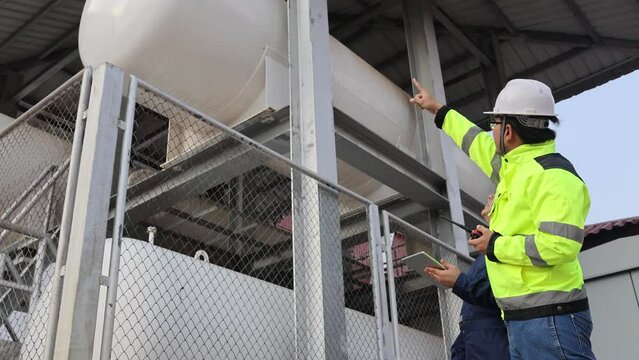 
Two men in safety gear are looking at a tablet. One of them is wearing a yellow jacket
