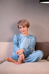woman in a blue home suit sitting on the sofa
