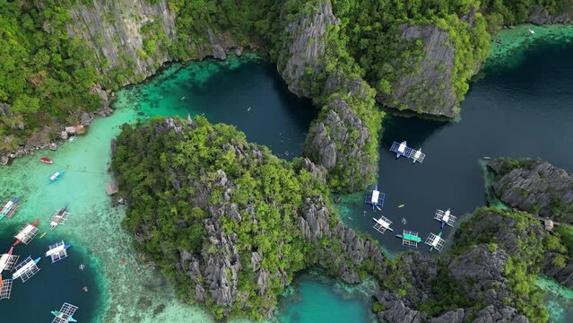 Aerial view of tropical island. Boats in blue lagoons, rocks cliffs mountains and coral reef, Philippines, 4k