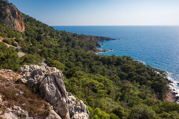 Fototapeta na wymiar Landscape with rocky cliffs, sandy beach, turquoise sea and vivid vegetation on hills, Lycian Way, Turkey