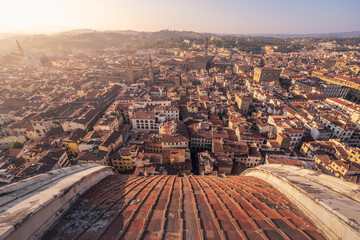 Historical city with high towers on palaces, tiled roofs and distant hills at sunrise, Florence,...