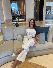 beautiful woman with dark hair in elegant clothes with accessories posing in luxury interiod of hotel hall - 790868070
