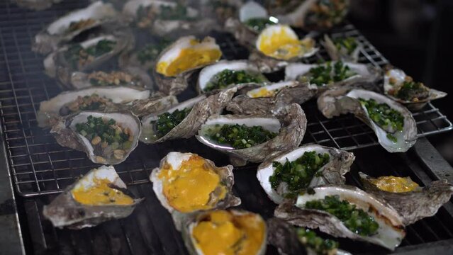 Delicious fresh grilled oysters, grilled with onion grease and cheese, on the charcoal stove