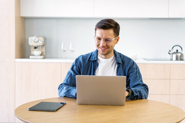 Elegant professional man in casual attire engages with a laptop, exuding contentment in a modern...