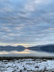 Serene winter landscape: snow blanketed field by crystal lake