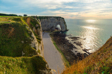 White chalk cliffs and natural arches of Etretat, Normandy, France. French sea coast in Normandie with famous rock formations at sunset. Travel destination